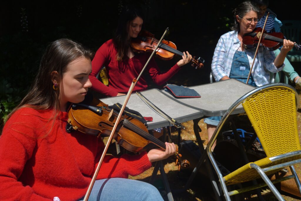 Trois femmes jouant du violon en extérieur