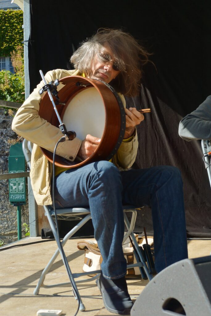 Homme jouant du bodhrán en concert extérieur