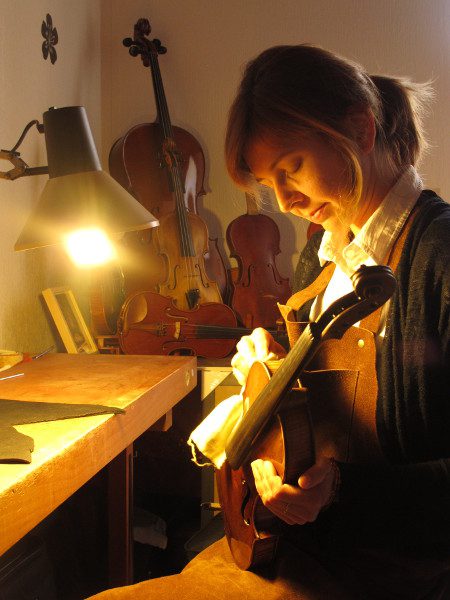 Femme ajustant violon dans atelier éclairé