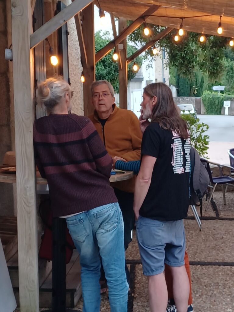 Trois personnes discutant sous des guirlandes lumineuses