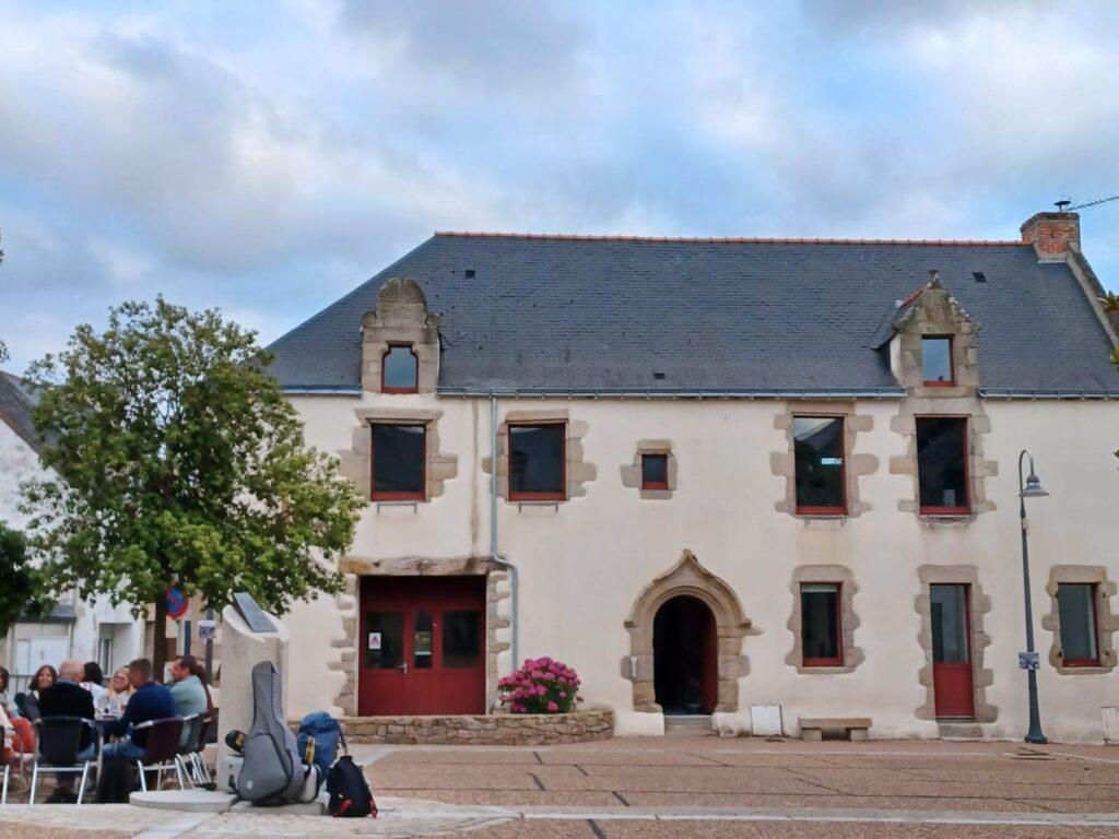 Personnes attablées devant bâtiment historique avec arbres.